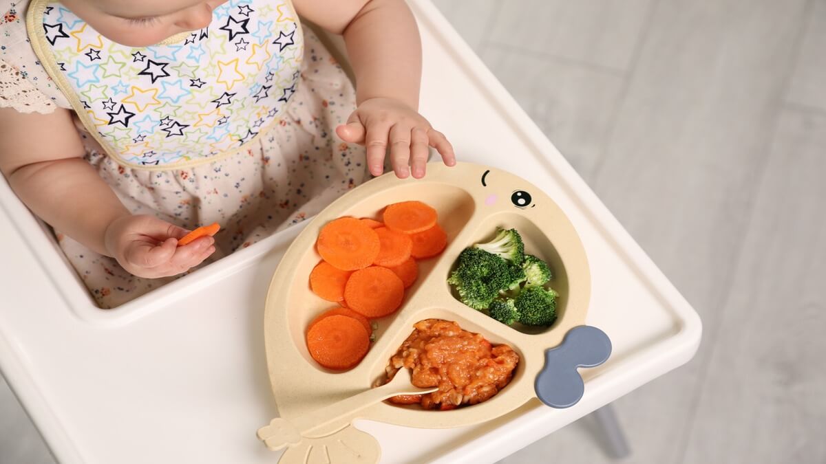 Bebe comiendo de un plato saludable.