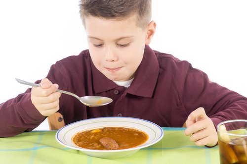 Un enfant qui mange un plat de lentilles.