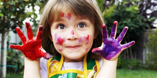 Une jeune fille avec ses mains pleines de peinture.