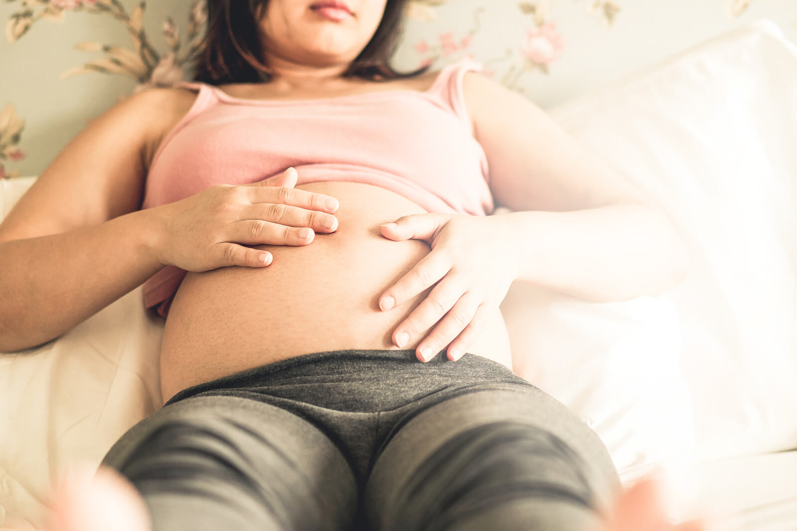 Mujer embarazada tocando su barriga y sintiendo las pataditas de su bebé.