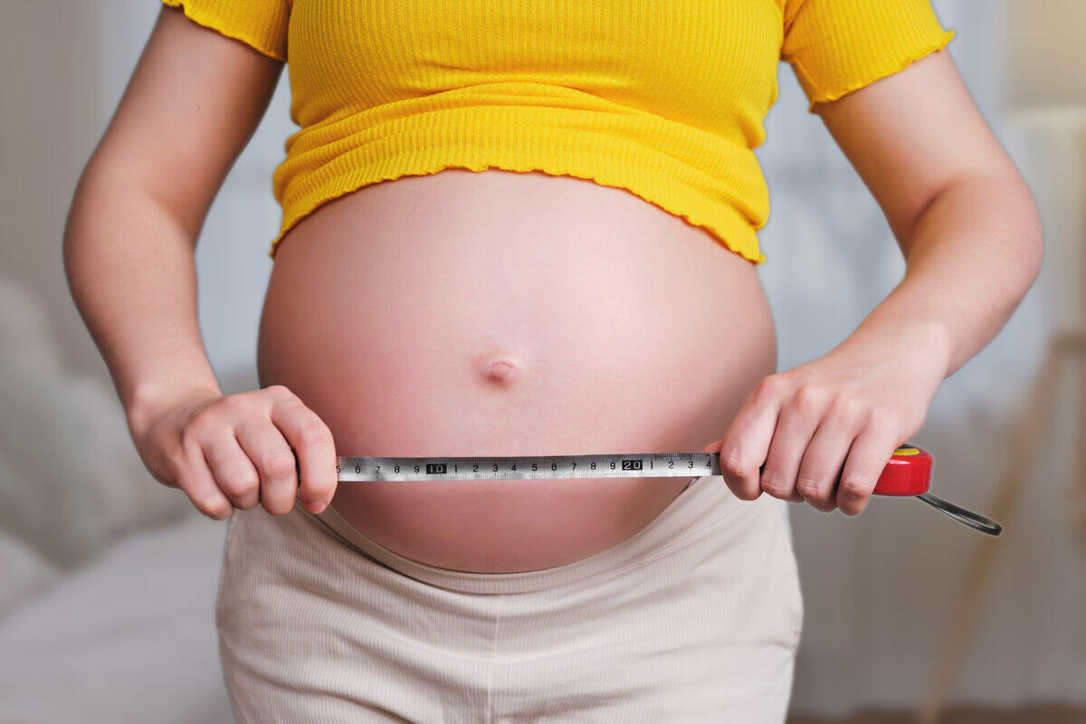 Mujer midiendo su embarazo con una cinta métrica