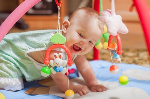 Un bébé qui joue sur un tapis d'éveil.