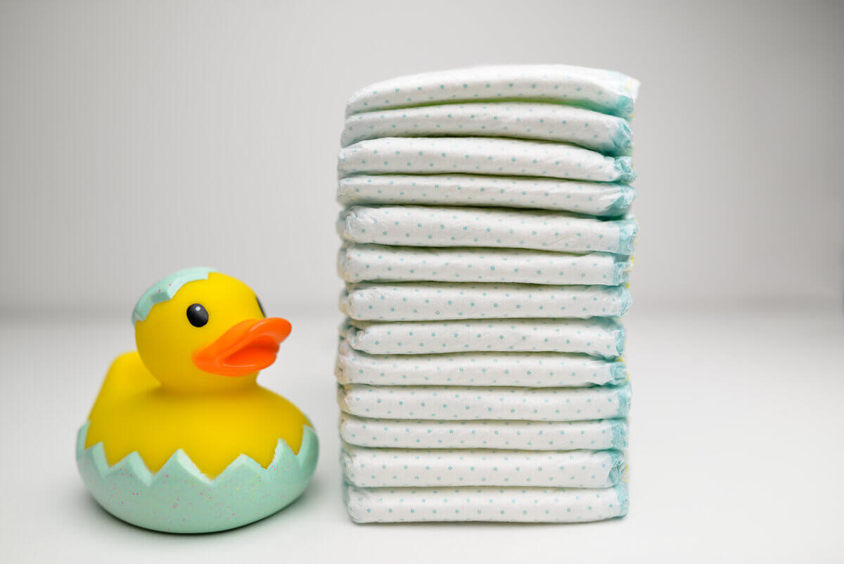 Gran pila de pañales acomodados con un patito de juguete al lado.