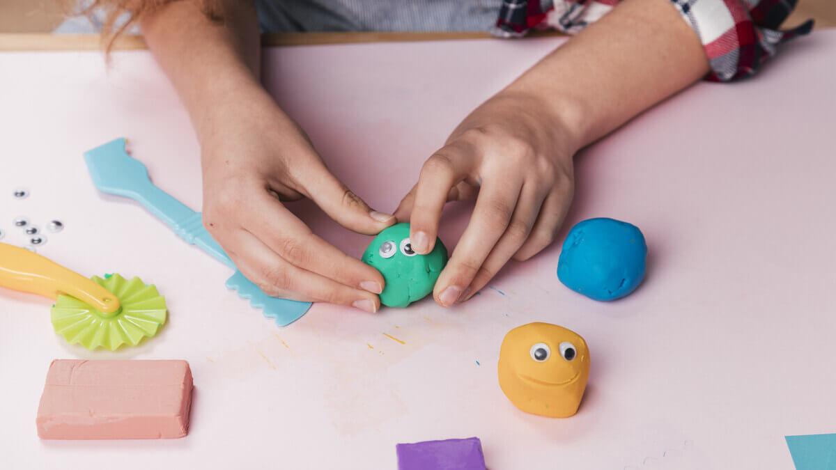 Mano femenina haciendo figuras con plastilina.