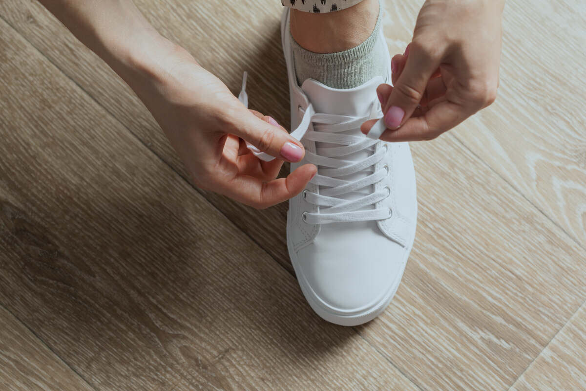 mujer atando cordones de zapatos.