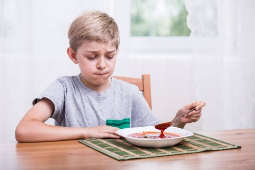 Niño con trastorno de alimentación selectiva con un plato de comida delante que no quiere comer.