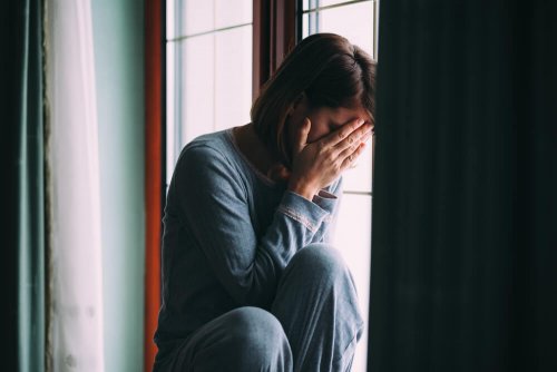 Mujer triste sentada en una ventana