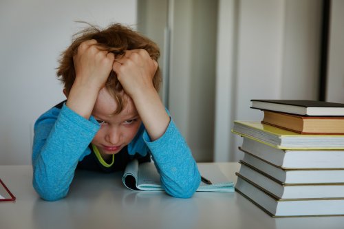 Niño estresado con los deberes porque no sigue los consejos para niños desorganizados.