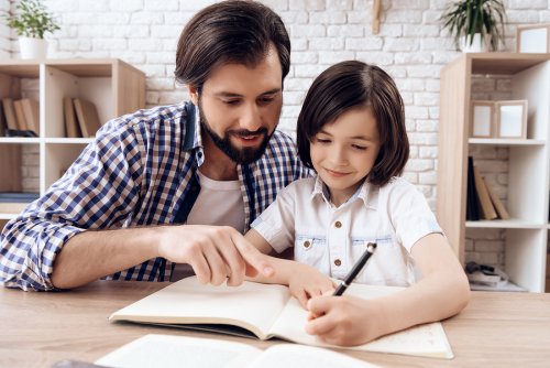 Padre ayudando a su hijo con los deberes en un buen espacio en casa.