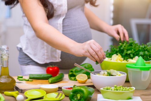 Une femme enceinte qui cuisine sainement.