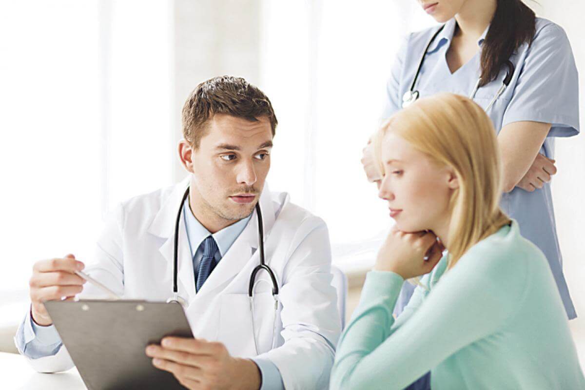A doctor and nurse talking to a female patient.