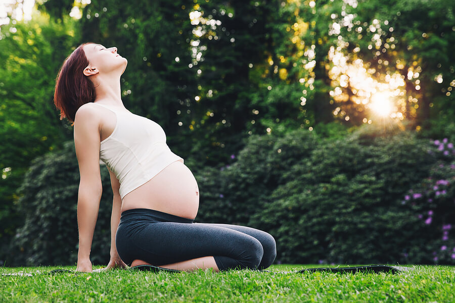 A pregnant women stretching in the sun.