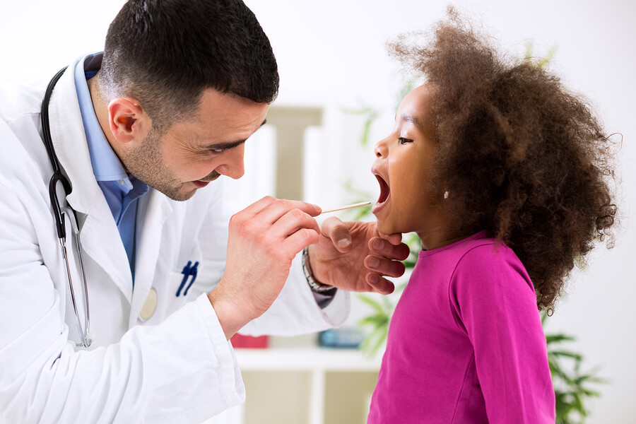 En lege som sjekker et barn for sykdommer som kan påvirke munnen.