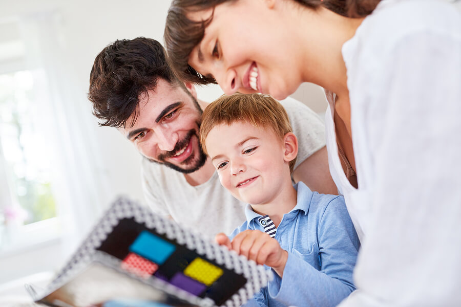 Deux parents qui regardent un livre avec leur enfant.