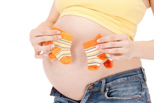 Embarazada de gemelos o mellizos con dos pares de calcetines sobre la barriga.