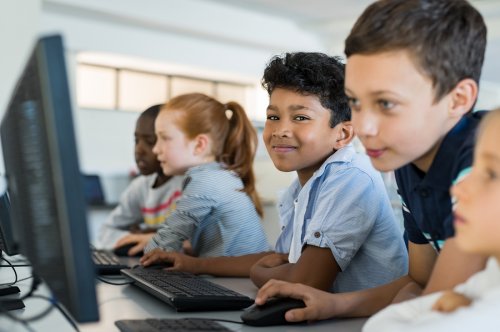Niños aprendiendo en el rincón del ordenador del aula.