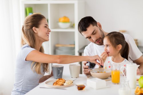 Madre y padre desayunando felices con su hija.