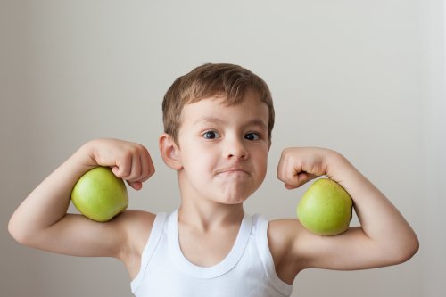 Niño con dos manzanas a modo de bíceps como parte de sus meriendas saludables para el recreo.