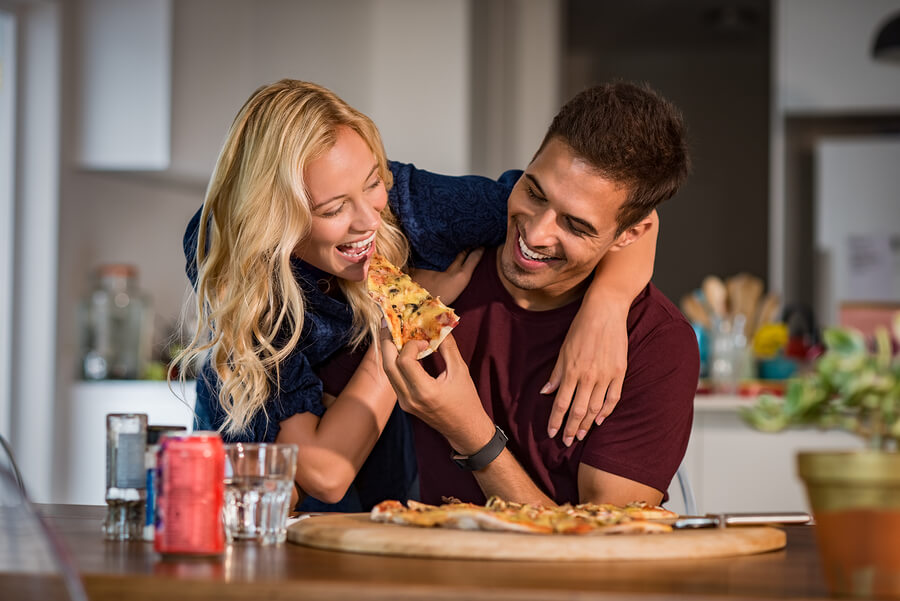 Una pareja muy feliz come pizza.