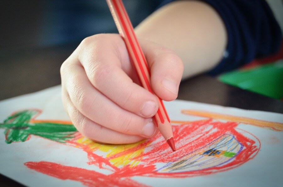 A child drawing a helicopter with colored pencils.