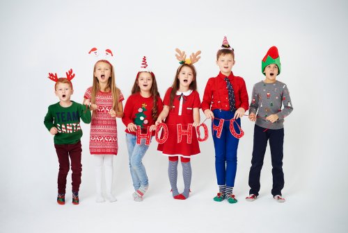Niños cantando villancicos con adornos de Navidad.