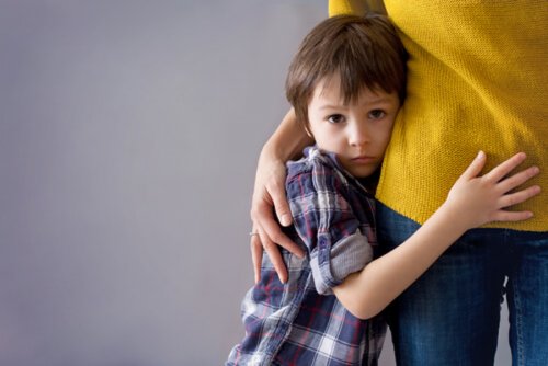 Niño con mucha timidez abrazado a su madre.