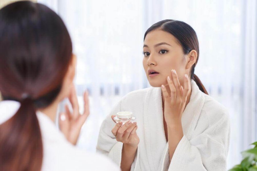A woman putting lotion on her face.