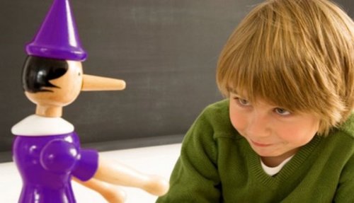 Niño con un muñeco de madera con la nariz larga por decir mentiras.