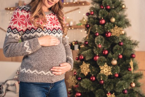 Mujer embarazada junto al árbol de Navidad.