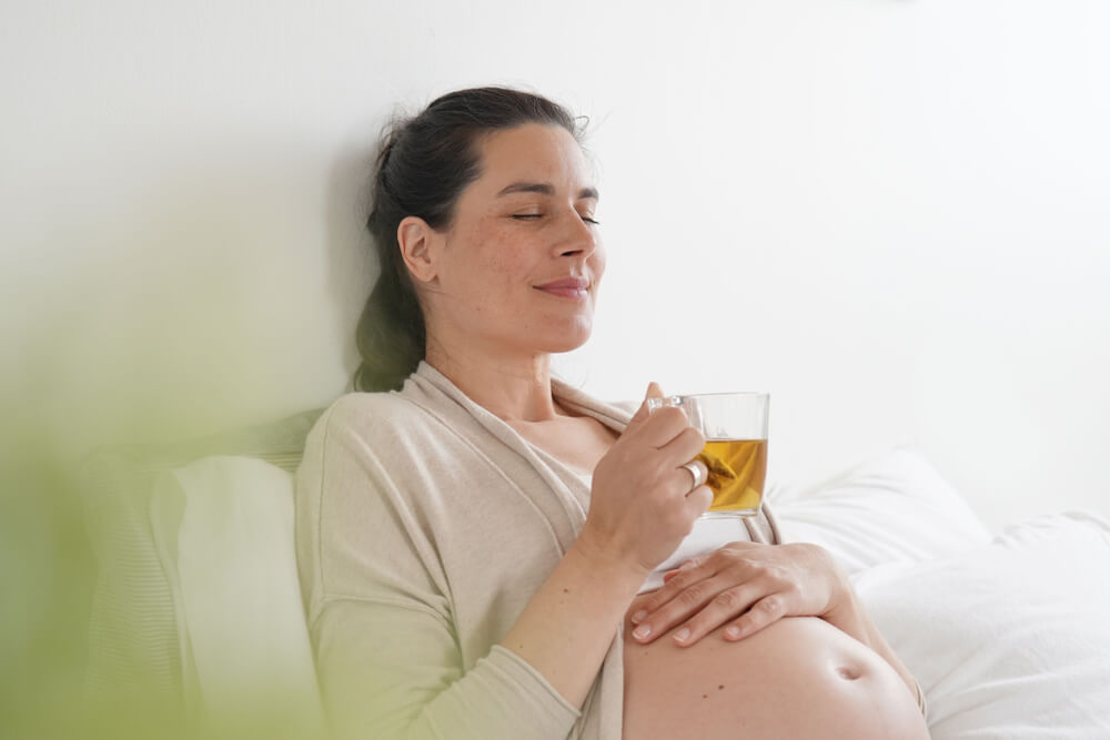 Mujer tomándose una infusión o un té verde en el embarazo.