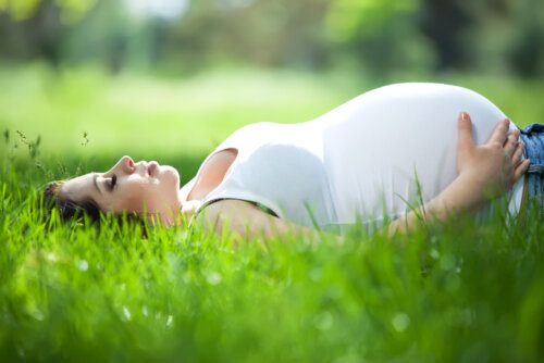 Mujer embarazada tumbada en el césped muy relajada.