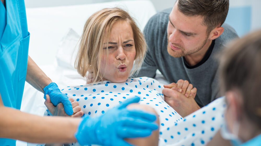Een vrouw is aan het persen tijdens de bevalling