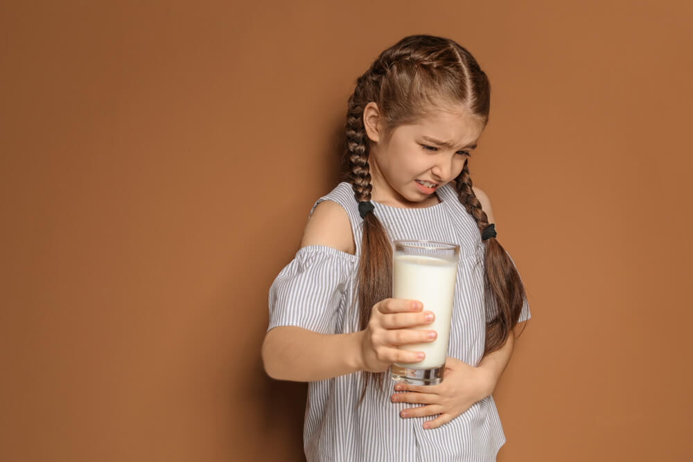 En ung tjej som har ont i magen efter att ha druckit mjölk.