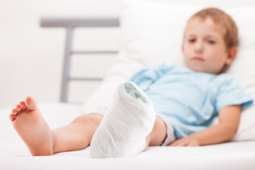Niño en la cama con la pierna escayolada.