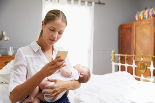 Mamá cuidando a su bebé y consultando una de las Apps.