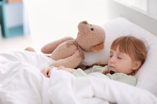 Niña durmiendo con su osito de peluche.