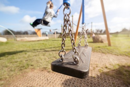 Niño jugando solo en el columpio del colegio.