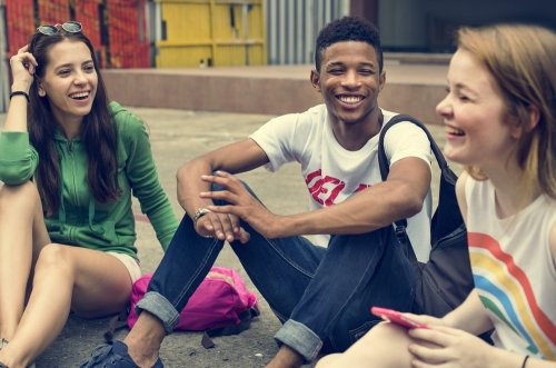 Teens sitting on the ground and laughing.