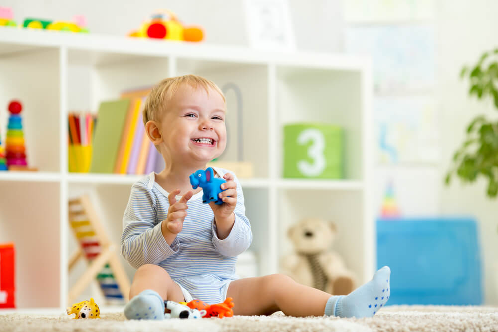 A toddler boy playing on the floor of his playroom.