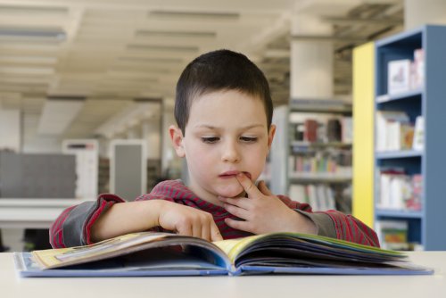 Niño con un libro para mejorar los procesos léxicos.