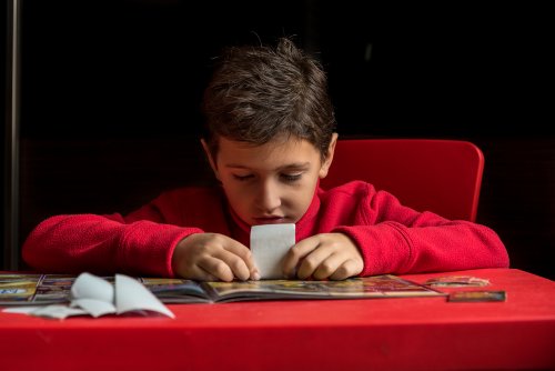 Niño pegando los cromos de sus colección en el álbum.