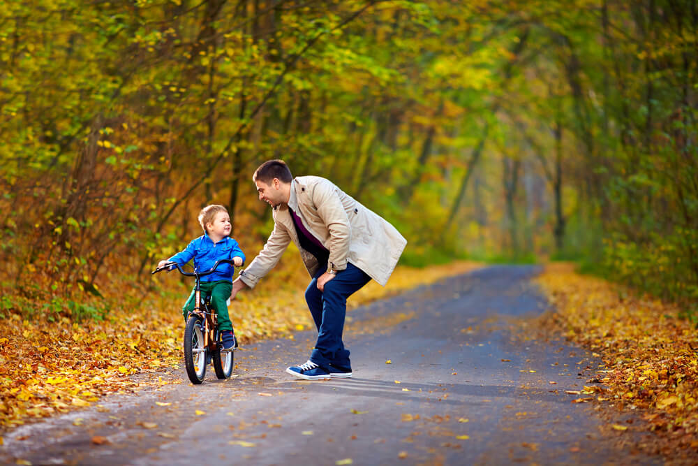 A father helping his young son to learn to ride a bike.