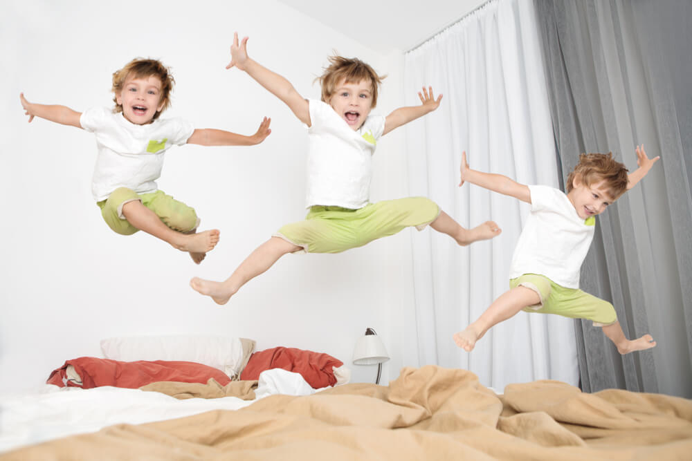 A hyper child jumping on a bed.