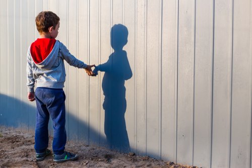 Niño con autismo mirando su sombra en una pared.