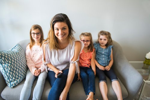 Une mère avec ses trois enfants sur un canapé.