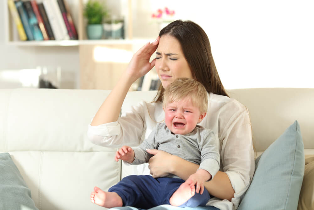 Une femme avec un bébé qui pleure sur ses genoux.