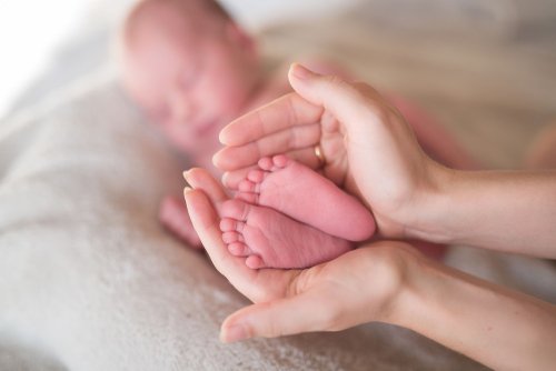 Madre con los pies del bebé entre las manos después del postparto.