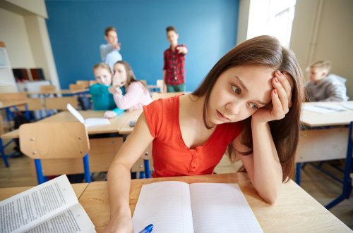 Niña sufriendo acoso escolar o bullying en clase antes de que el profesor pase el test sociométrico.