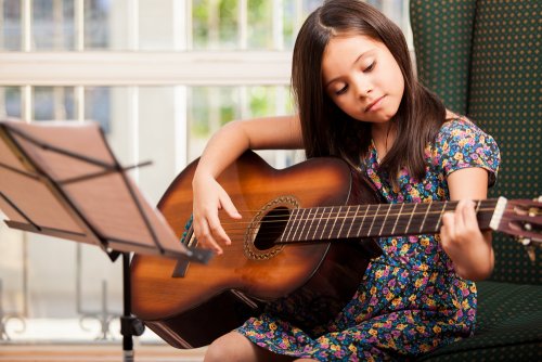Niña aprendiendo a tocar la guitarra en una de las actividades extraescolares a las que asiste.