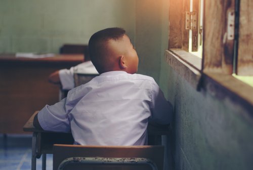 Niño en clase mirando por la ventana.